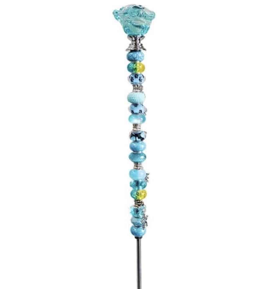 A decorative beaded garden stake DIY, featuring a metal stick adorned with blue, green, and silver beads, topped with a charming blue glass bear-shaped ornament.